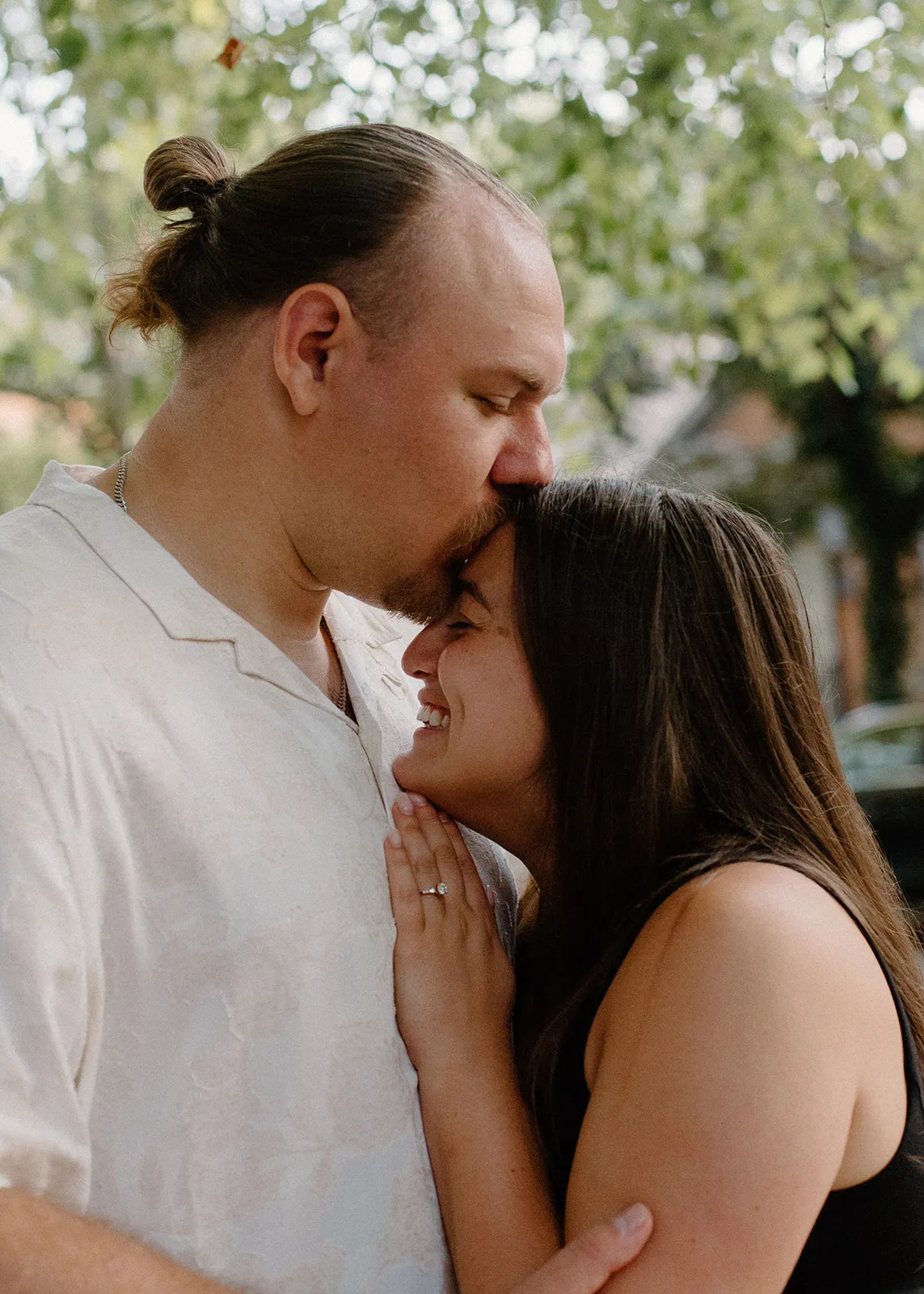 Jacob kissing Gina on the forehead under the trees