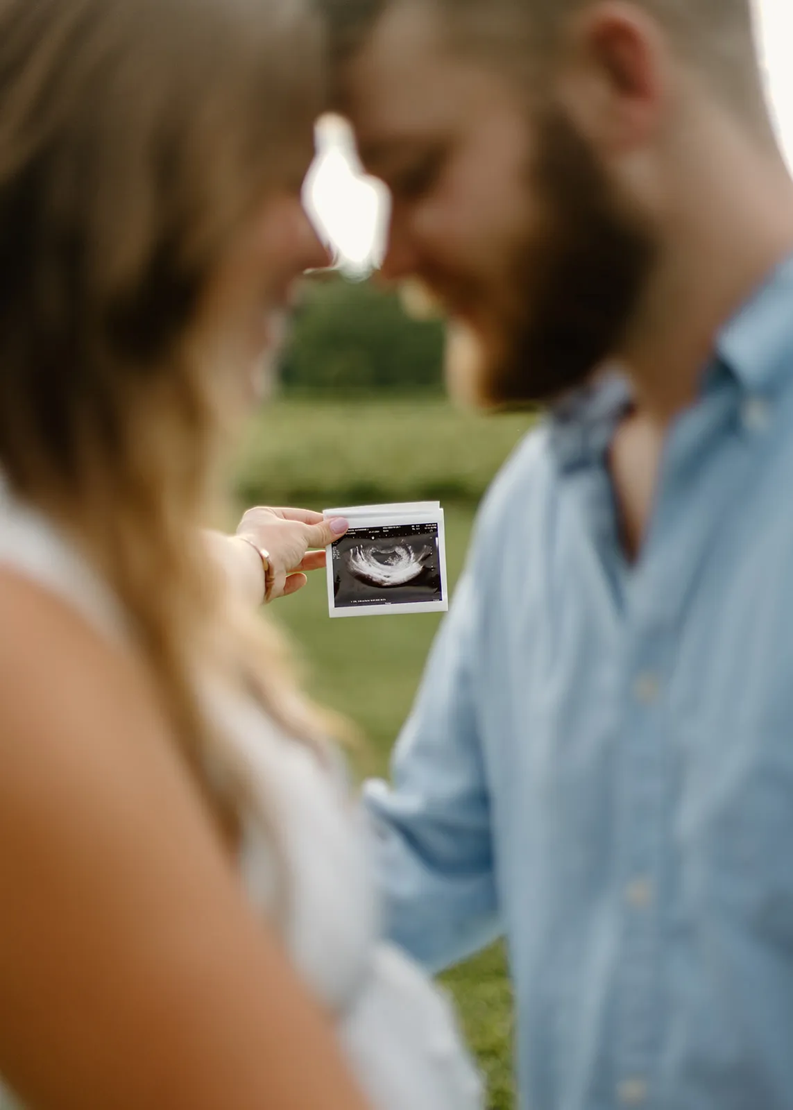 A single ultrasound photo held up between them, foreheads touching