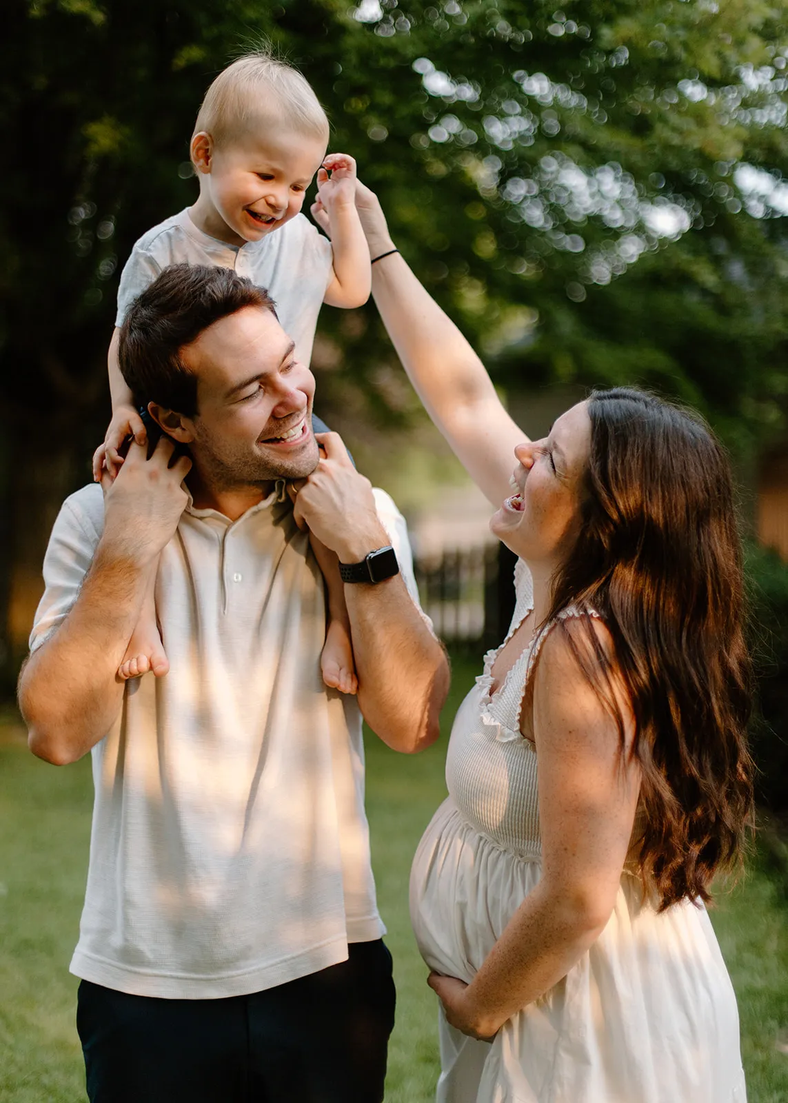 Mom reaching up to tickle their son on dad's shoulders